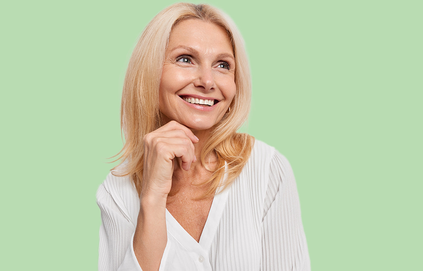 Femme blonde souriante tenant son visage, illustrant les bienfaits du Booster Collagène des Boosters Naturels pour une peau éclatante et un bien-être naturel